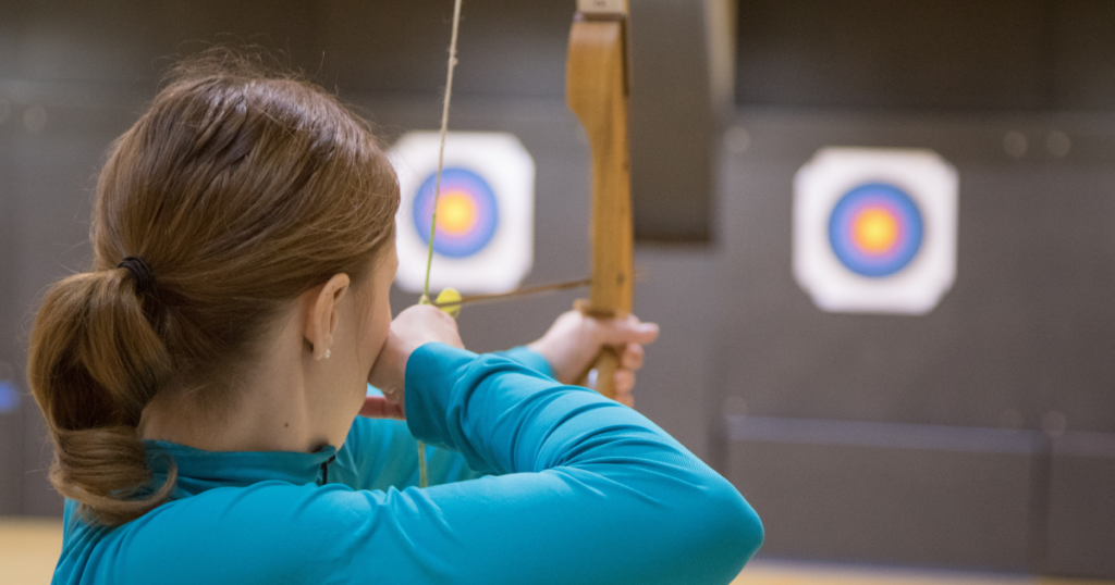 Woman archer about to release an arrow towards a target