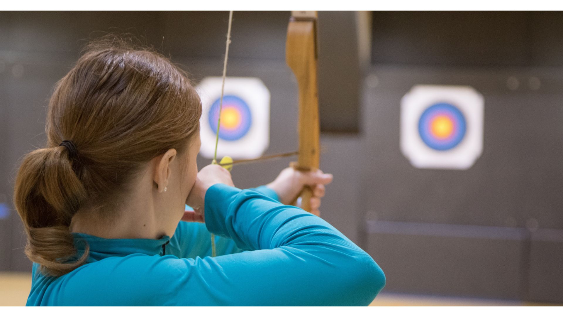 Woman archer about to release an arrow towards a target